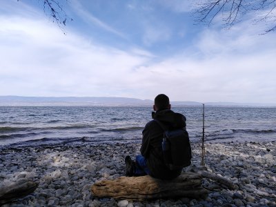 Le troubadour de l'instinct présent et son carnet contemplant une vue panoramique sur un lac